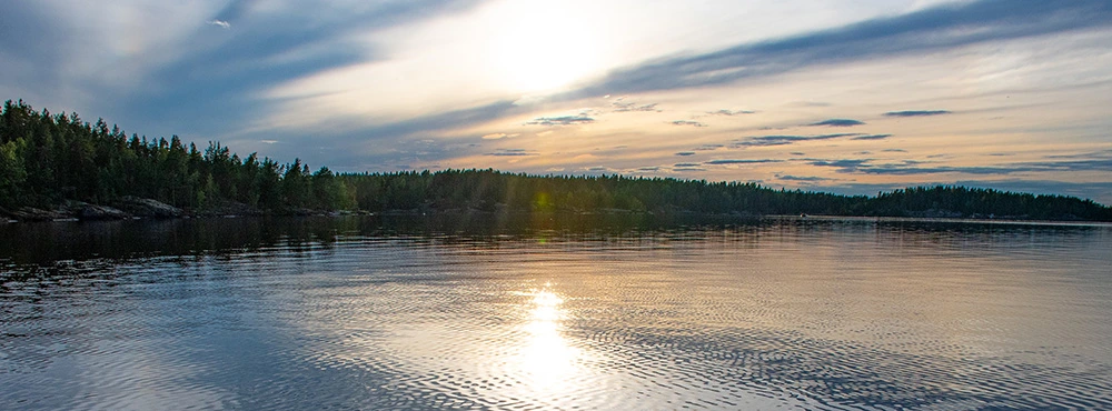 Upea ja rauhallinen maisema Saimaalla keskiyön auringon aikaan.